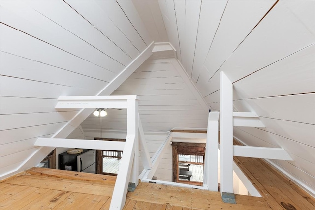 stairs with lofted ceiling and wooden walls