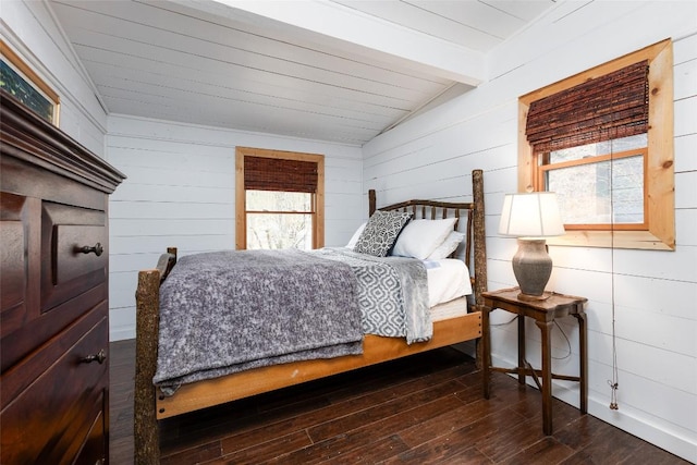 bedroom with vaulted ceiling with beams, multiple windows, and hardwood / wood-style flooring