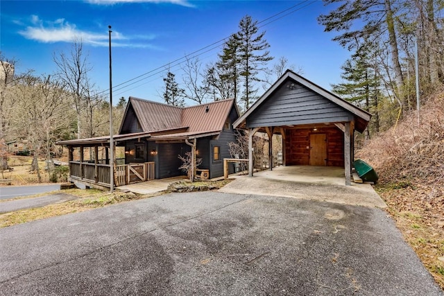 rustic home featuring metal roof, a porch, aphalt driveway, and a detached carport