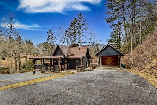 view of front facade with aphalt driveway, covered porch, and metal roof