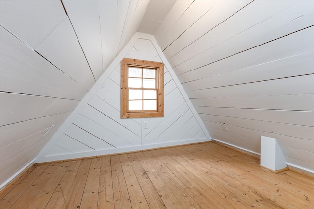 bonus room featuring hardwood / wood-style flooring, vaulted ceiling, and wood walls