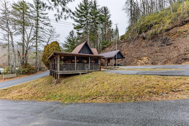 view of front of home with a porch, a front yard, metal roof, and driveway