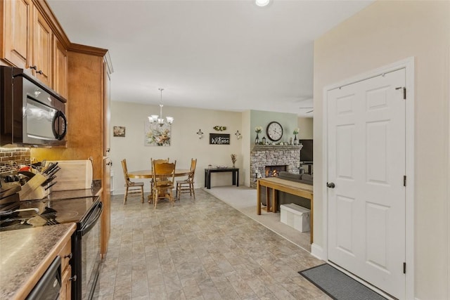210 Triple Fork Rd, Cullowhee, NC 28723 - kitchen featuring black appliances, brown cabinetry, a fireplace, a chandelier, and tasteful backsplash