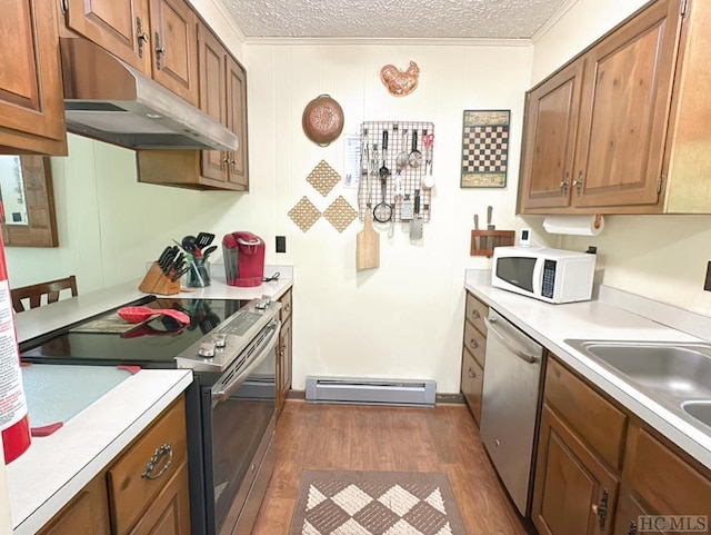 kitchen with dark hardwood / wood-style floors, a baseboard radiator, stainless steel appliances, crown molding, and a textured ceiling