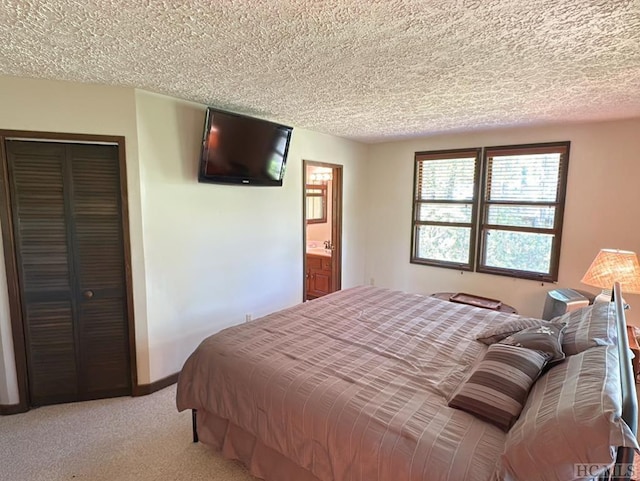 carpeted bedroom with a closet, a textured ceiling, and ensuite bathroom