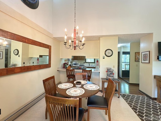 dining space with a baseboard radiator, a chandelier, and a towering ceiling