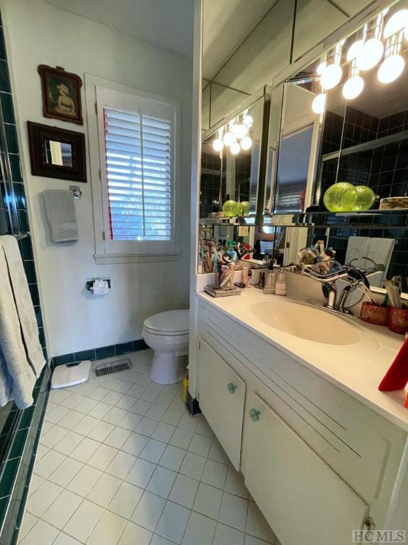 bathroom featuring tile patterned flooring, vanity, walk in shower, and toilet