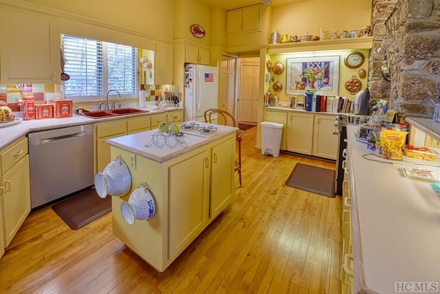 kitchen with sink, white fridge, a center island, stainless steel dishwasher, and light hardwood / wood-style floors