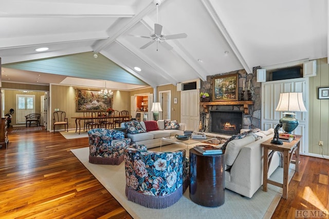 living room featuring ceiling fan with notable chandelier, a stone fireplace, vaulted ceiling with beams, and wood-type flooring