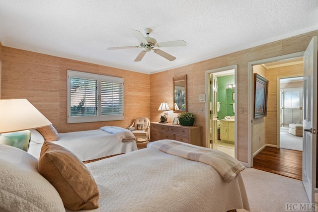 bedroom featuring connected bathroom, ceiling fan, carpet flooring, and a textured ceiling