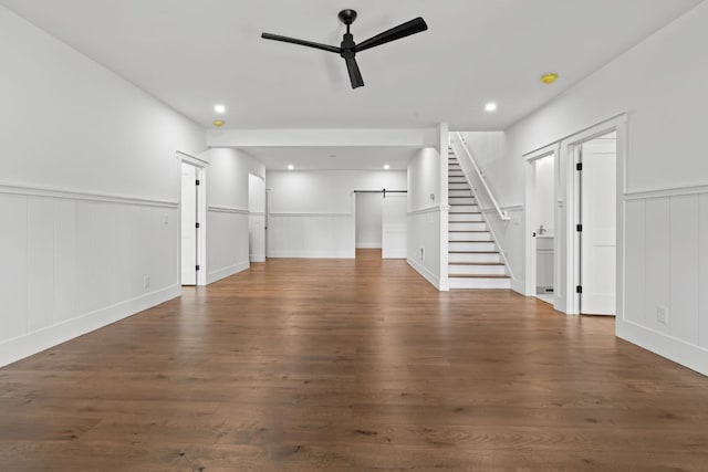 1310 New Settlers Way, Glenville, NC 28736 - unfurnished living room featuring ceiling fan, stairs, wainscoting, wood finished floors, and a decorative wall