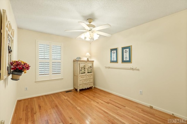 unfurnished room featuring ceiling fan, light wood-type flooring, and a textured ceiling