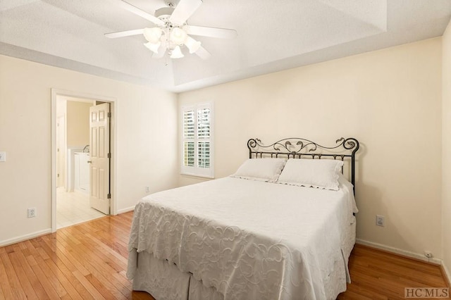 bedroom with a raised ceiling, hardwood / wood-style flooring, and ceiling fan