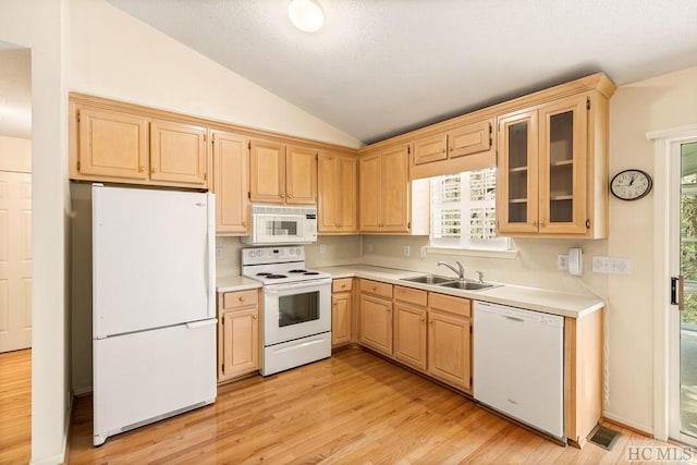 kitchen with sink, white appliances, vaulted ceiling, and plenty of natural light