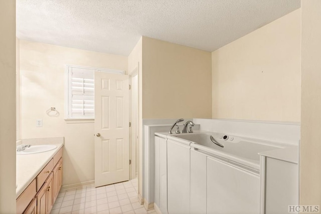 full bath with a garden tub, tile patterned floors, a textured ceiling, vanity, and baseboards