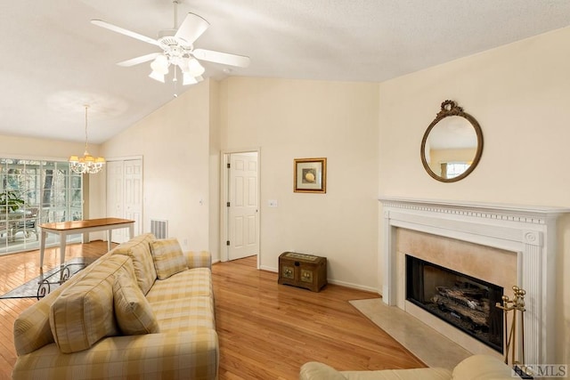 living room featuring vaulted ceiling, visible vents, a premium fireplace, baseboards, and light wood-style flooring