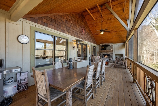 sunroom featuring a ceiling fan, wooden ceiling, a fireplace, and lofted ceiling with beams