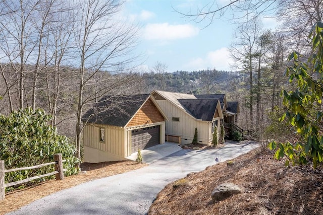 view of front of house with board and batten siding, crawl space, fence, a garage, and a forest view