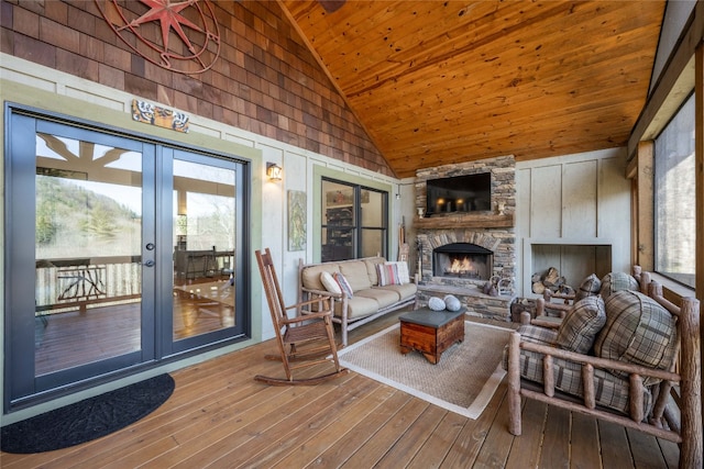 living room featuring french doors, wood-type flooring, wood ceiling, a stone fireplace, and high vaulted ceiling