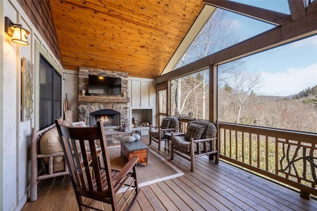 sunroom / solarium with vaulted ceiling, wooden ceiling, and a fireplace