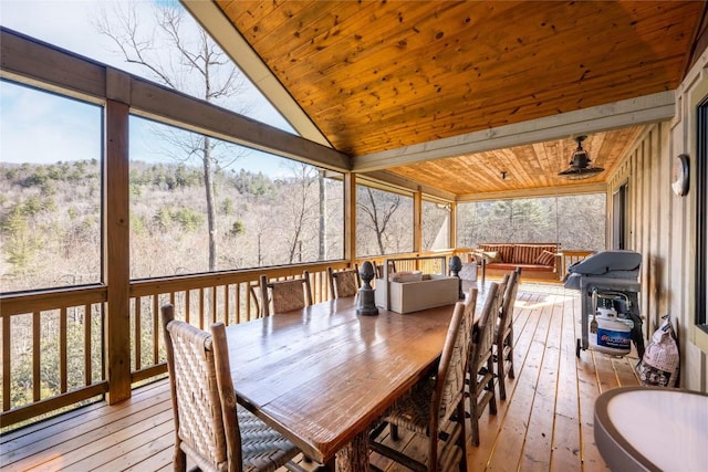 sunroom / solarium featuring wood ceiling, vaulted ceiling, and a view of trees