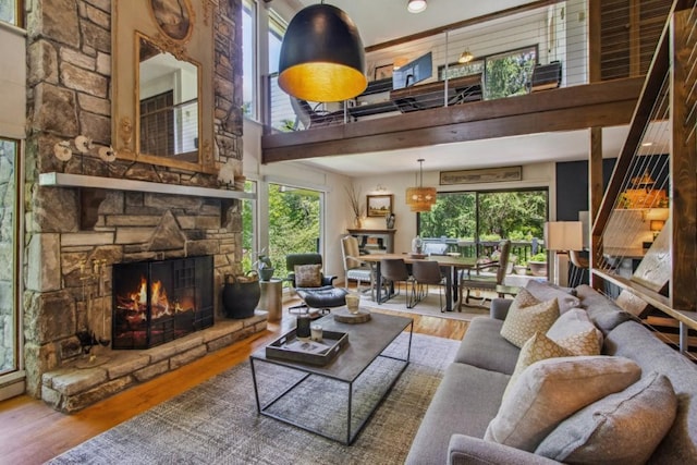 15 Elm Ct, Highlands, NC 28741 - living area with a stone fireplace, wood finished floors, a towering ceiling, healthy amount of natural light, and stairs