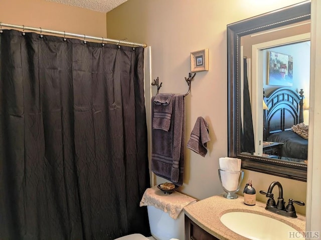 bathroom featuring walk in shower, vanity, toilet, and a textured ceiling