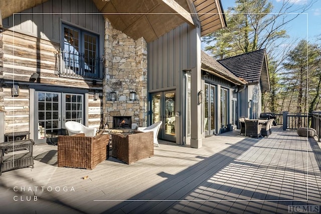 wooden terrace with an outdoor living space with a fireplace