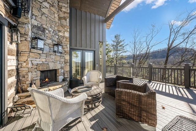 wooden terrace with an outdoor stone fireplace and french doors