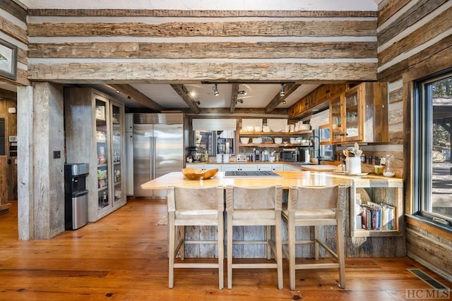 kitchen with beamed ceiling, a breakfast bar, kitchen peninsula, and appliances with stainless steel finishes