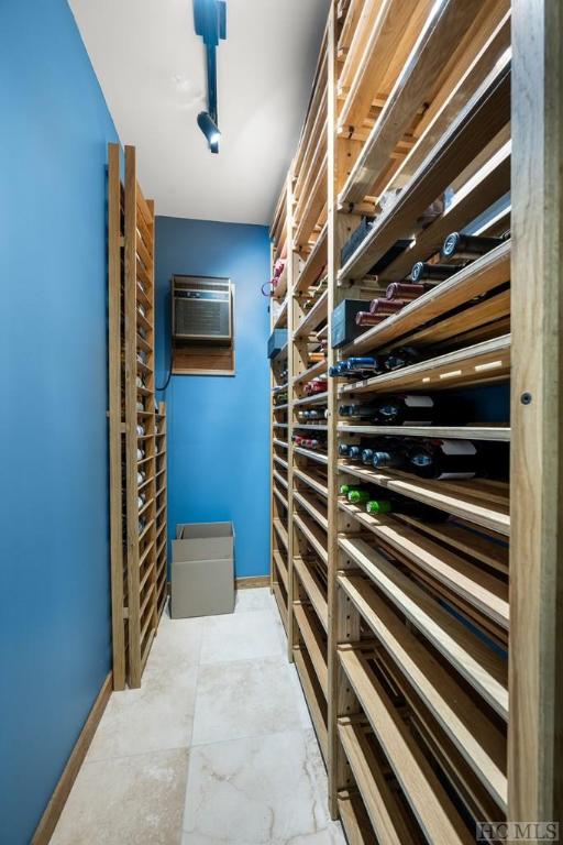 wine area with a wall mounted air conditioner and rail lighting