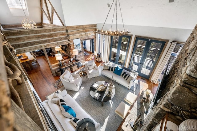 living room featuring hardwood / wood-style floors, a notable chandelier, high vaulted ceiling, and french doors