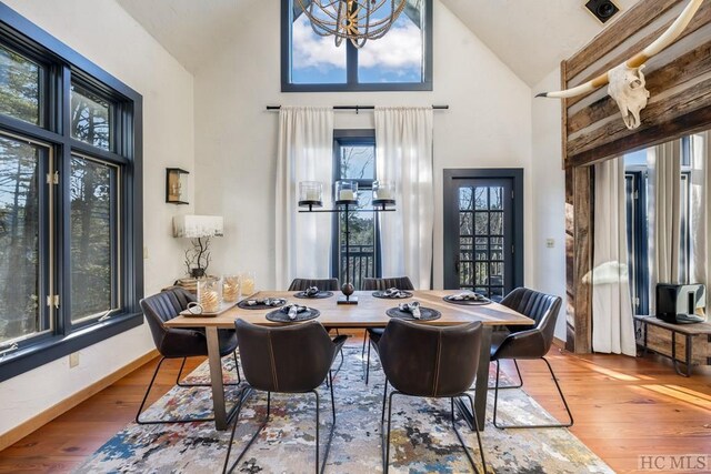 dining room with high vaulted ceiling and wood-type flooring