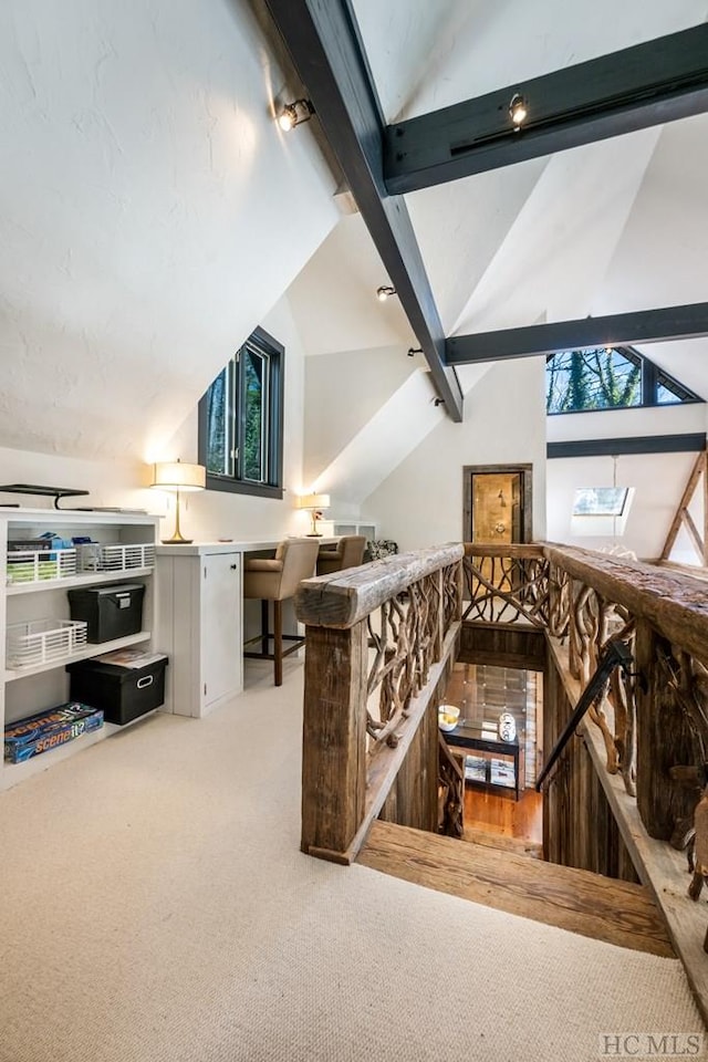 interior space featuring light colored carpet and vaulted ceiling with skylight