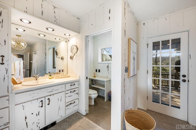 bathroom featuring vanity, wooden walls, and toilet