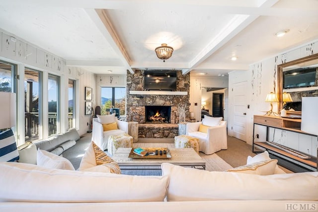 carpeted living room featuring a stone fireplace and beam ceiling