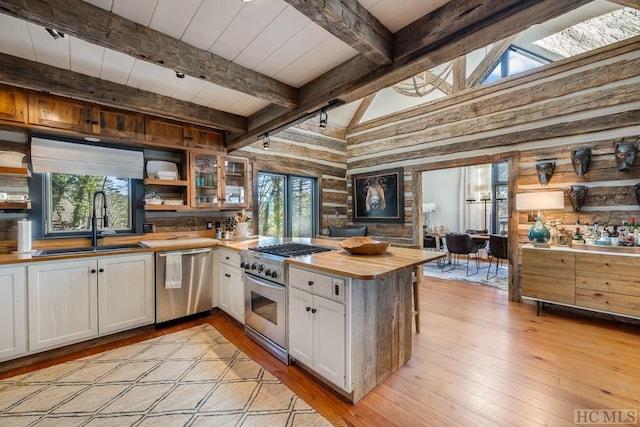 kitchen with sink, wooden counters, light wood-type flooring, stainless steel appliances, and white cabinets