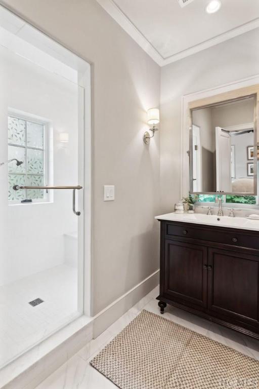 bathroom featuring walk in shower, ornamental molding, and vanity