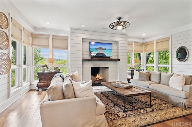 living room featuring crown molding, a fireplace, and light wood-type flooring