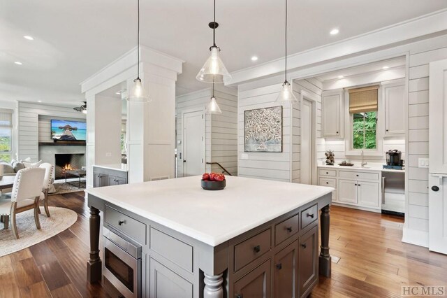 kitchen featuring pendant lighting, white cabinetry, dark hardwood / wood-style floors, stainless steel microwave, and a kitchen island