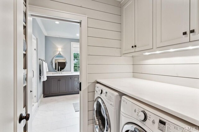 laundry area with wooden walls, cabinets, and washing machine and clothes dryer