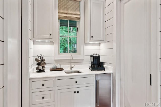 bar featuring sink, white cabinets, and beverage cooler