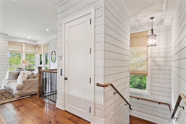 interior space with hardwood / wood-style flooring, wooden walls, and crown molding