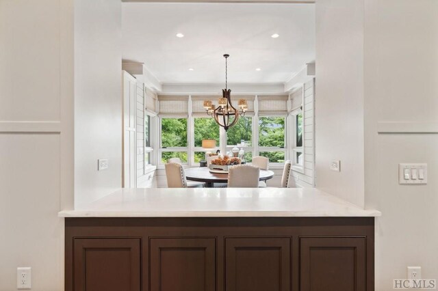 kitchen featuring crown molding, dark brown cabinets, and a chandelier