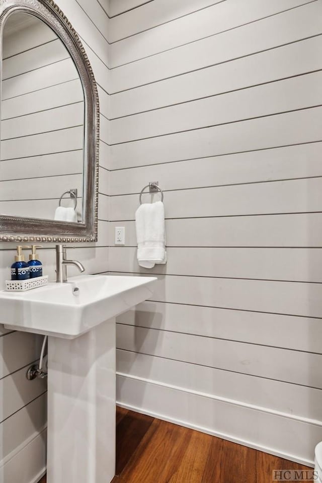 bathroom with hardwood / wood-style floors and wooden walls