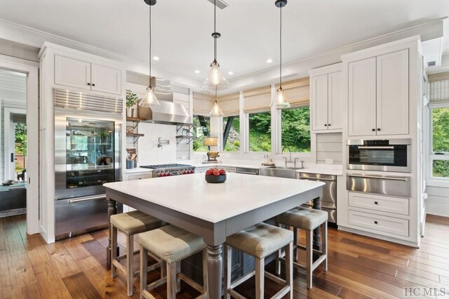 kitchen featuring appliances with stainless steel finishes, a kitchen bar, a center island, and white cabinets