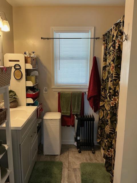 bathroom featuring radiator heating unit, vanity, tile patterned flooring, and curtained shower