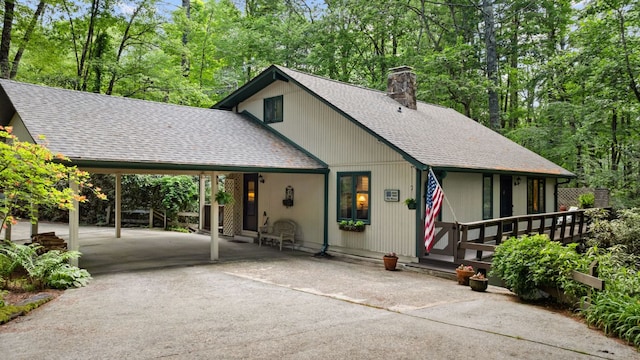 145 Mount Lori Dr, Highlands, NC 28741 - view of front of house with a shingled roof, a chimney, asphalt driveway, an attached carport, and view of wooded area