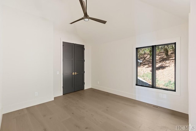 unfurnished room featuring lofted ceiling, hardwood / wood-style floors, a healthy amount of sunlight, and ceiling fan