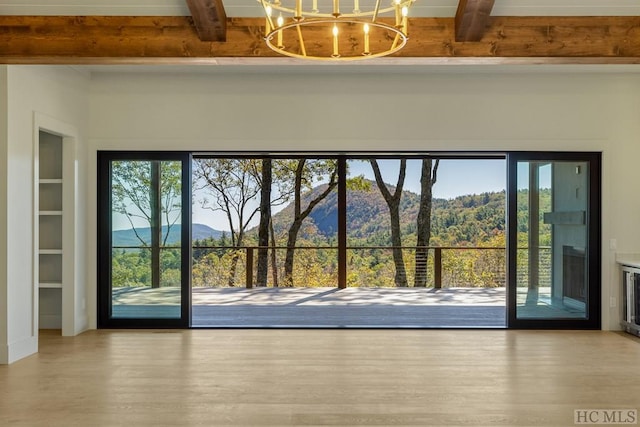 entryway featuring a wealth of natural light, a mountain view, a chandelier, and beam ceiling